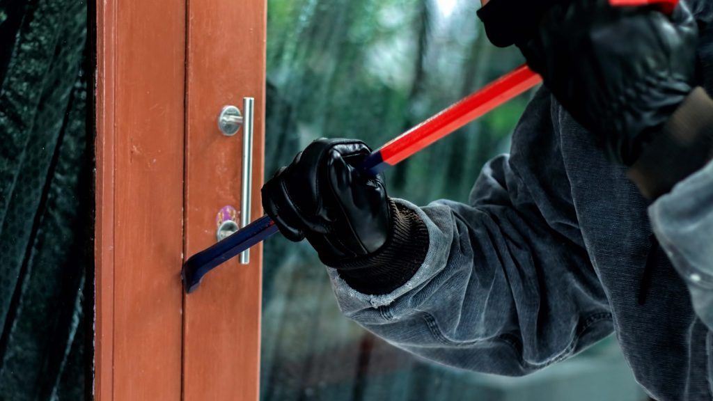 Theif using crowbar to break into a house